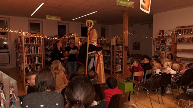 Nikolaus und Mitglieder des Bibliotheksteams "spielen" die Legende von Nikolaus und den drei armen Töchtern: Vater dankt Nikolaus
